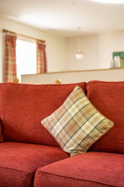 Plaid patterned cushion on a red sofa inside the luxury Salutation Apartment at Netherby Hall