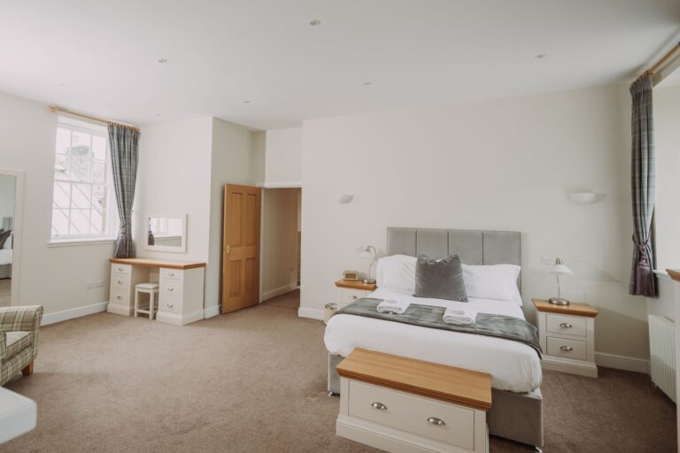 Spacious bedroom in the Sir Walter Scott Apartment at Netherby Hall, featuring a luxury double bed and elegant decor