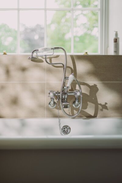 Chrome bathtub faucet with handheld shower attachment in the Sir Walter Scott Apartment at Netherby Hall