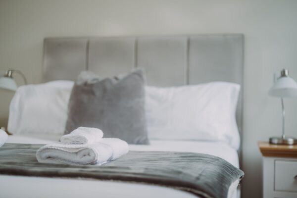 Neatly folded white towels on a bed with grey pillows in the luxury Sir Walter Scott Apartment at Netherby Hall