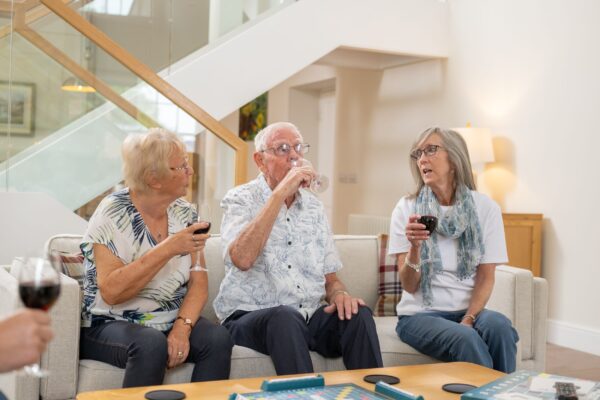 Three elderly friends enjoying wine while relaxing in the living area of the Sir Walter Scott Apartment at Netherby Hall