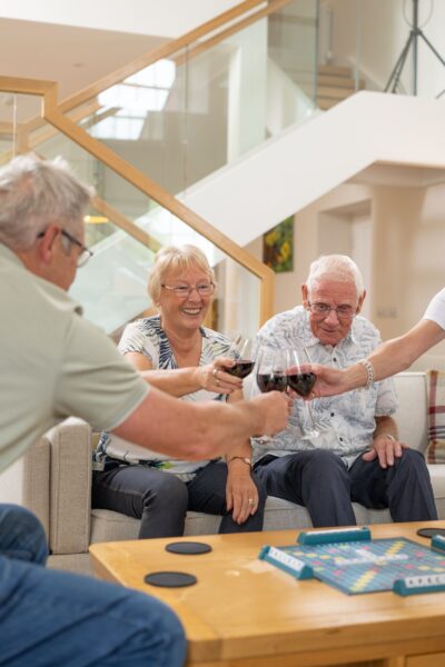 Happy group of seniors enjoying wine and board games inside the luxury Sir Walter Scott Apartment at Netherby Hall