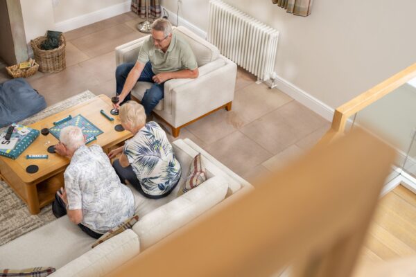 Three people enjoying a board game in the bright, modern living room of the Sir Walter Scott Apartment at Netherby Hall