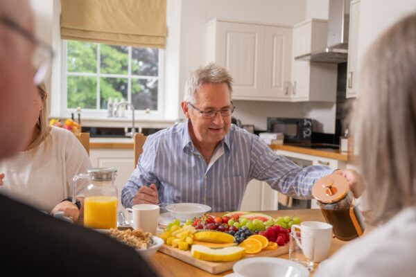 A group of people enjoying a breakfast spread with fresh fruit and juice in the dining area of Sir Walter Scott Apartment