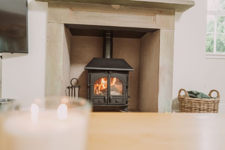 A cozy wood-burning stove with a warm fire burning inside, located in the Sir Walter Scott Apartment at Netherby Hall