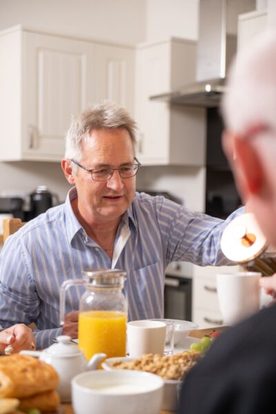 A man enjoying breakfast with fresh juice and pastries in the kitchen of the Sir Walter Scott Apartment at Netherby Hall