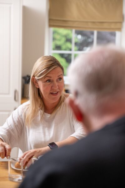 A smiling woman enjoying a meal at a dining table in the luxury Sir Walter Scott Apartment at Netherby Hall