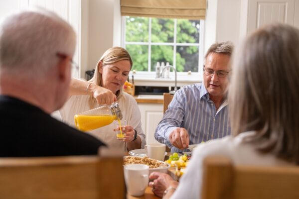 Group of friends enjoying breakfast in the bright kitchen of the Sir Walter Scott Apartment at Netherby Hall, Cumbria
