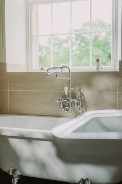 White freestanding bathtub with chrome faucet and a large window in the Sir Walter Scott Apartment at Netherby Hall