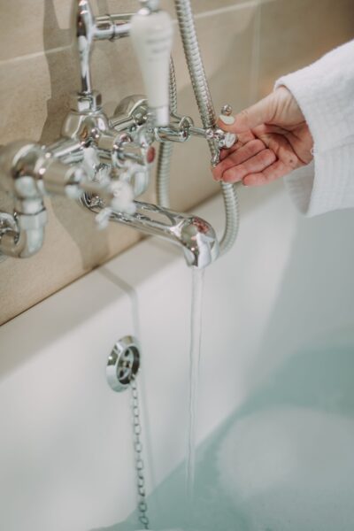 Person catching water from a luxury chrome bathtub faucet in the Sir Walter Scott Apartment at Netherby Hall