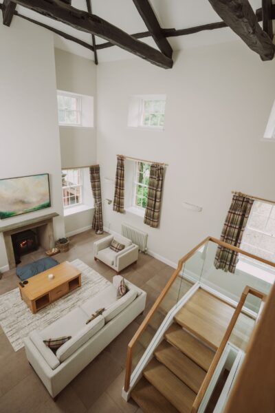 Modern living room in Sir Walter Scott Apartment featuring high ceilings, exposed beams, a fireplace, and a contemporary sofa
