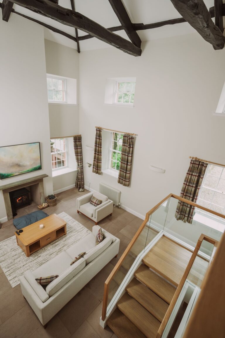 Modern living room in Sir Walter Scott Apartment featuring high ceilings, exposed beams, a fireplace, and a contemporary sofa