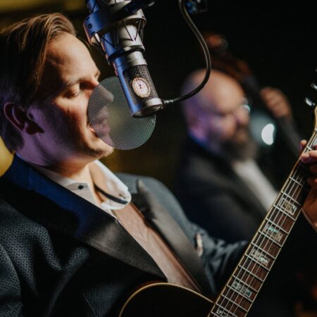 Musician David Toule, multi-instrumentalist jazz vocalist, performing with a guitar and microphone at Netherby Hall luxury self-catering accommodation in Cumbria