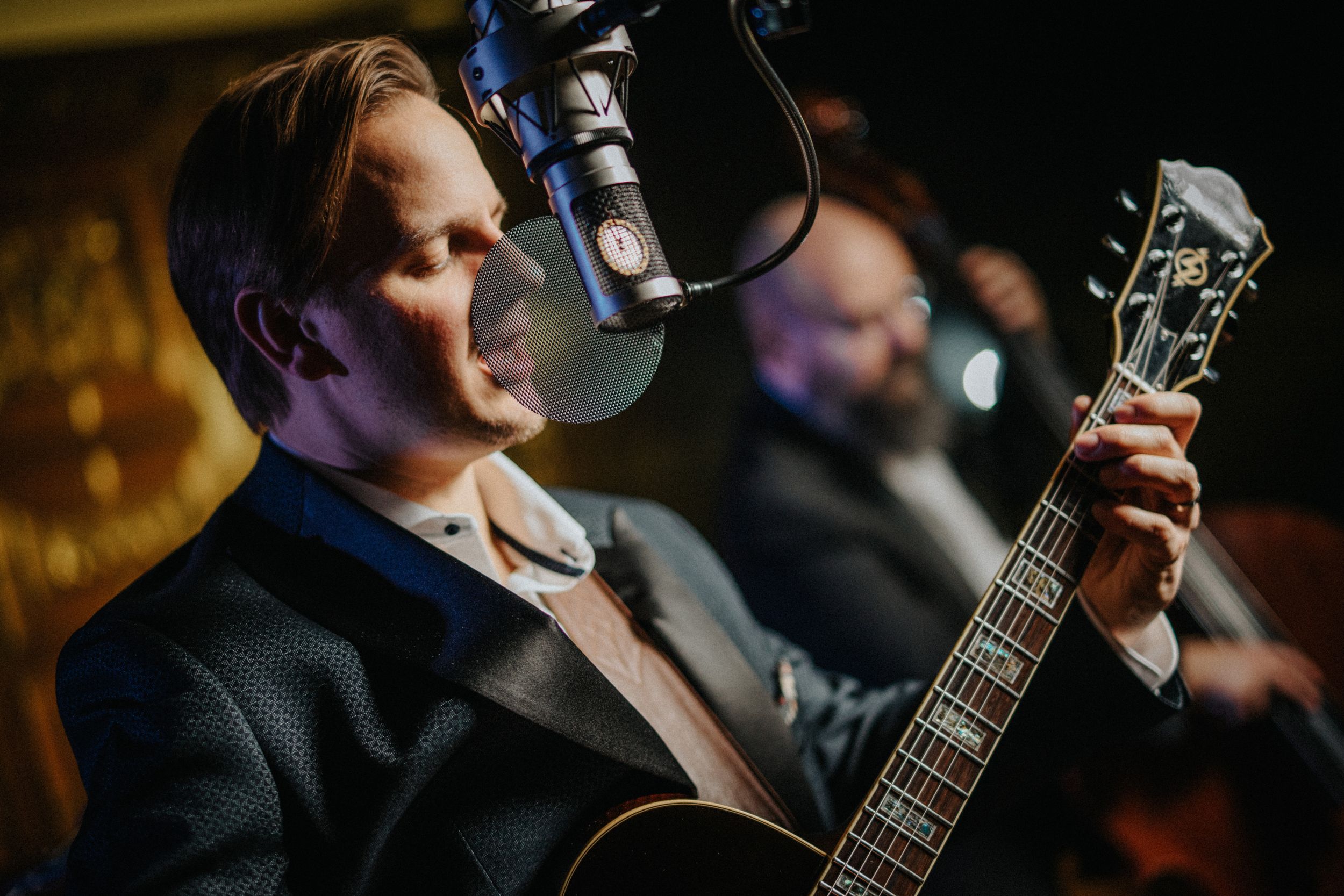 Musician David Toule, multi-instrumentalist jazz vocalist, performing with a guitar and microphone at Netherby Hall luxury self-catering accommodation in Cumbria